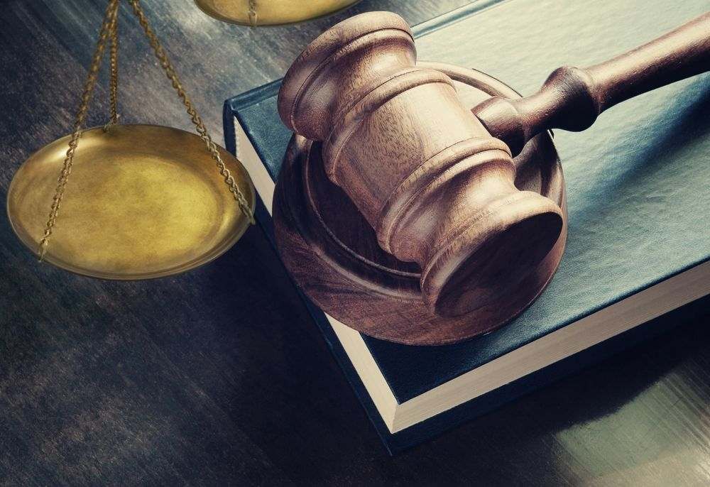 Judge gavel on legal book and brass scale on wooden table