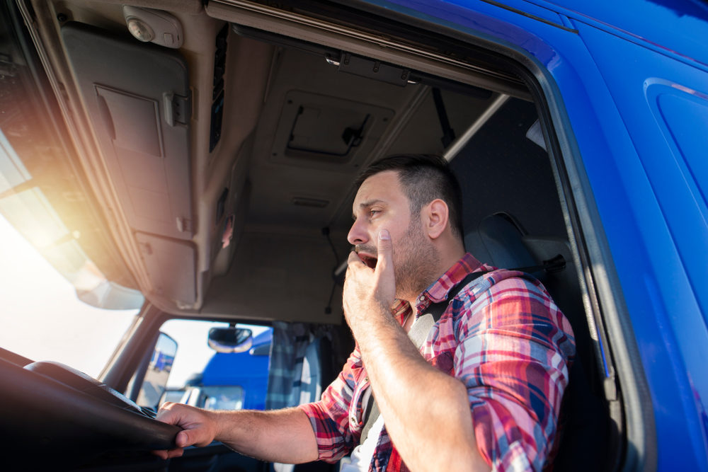 fatigued truck driver yawning as his shift reaches the hours of service rules maximum