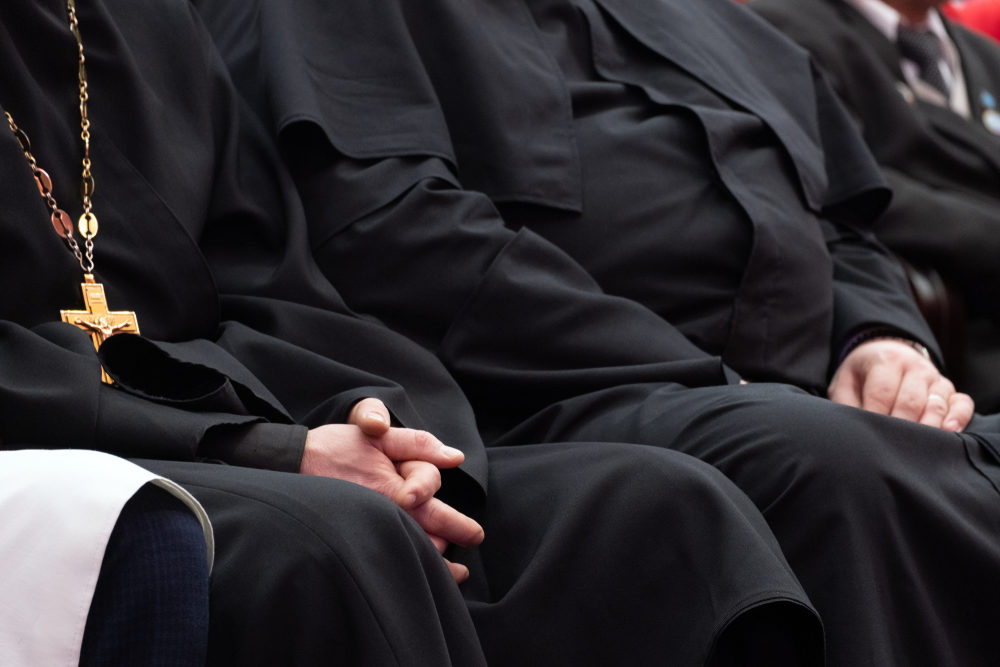 Clergy members in black robes sit together