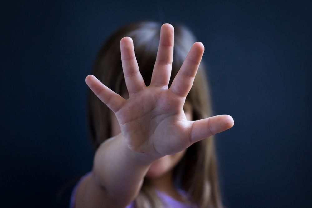 young girl holding up her hand to stop child sex abuse